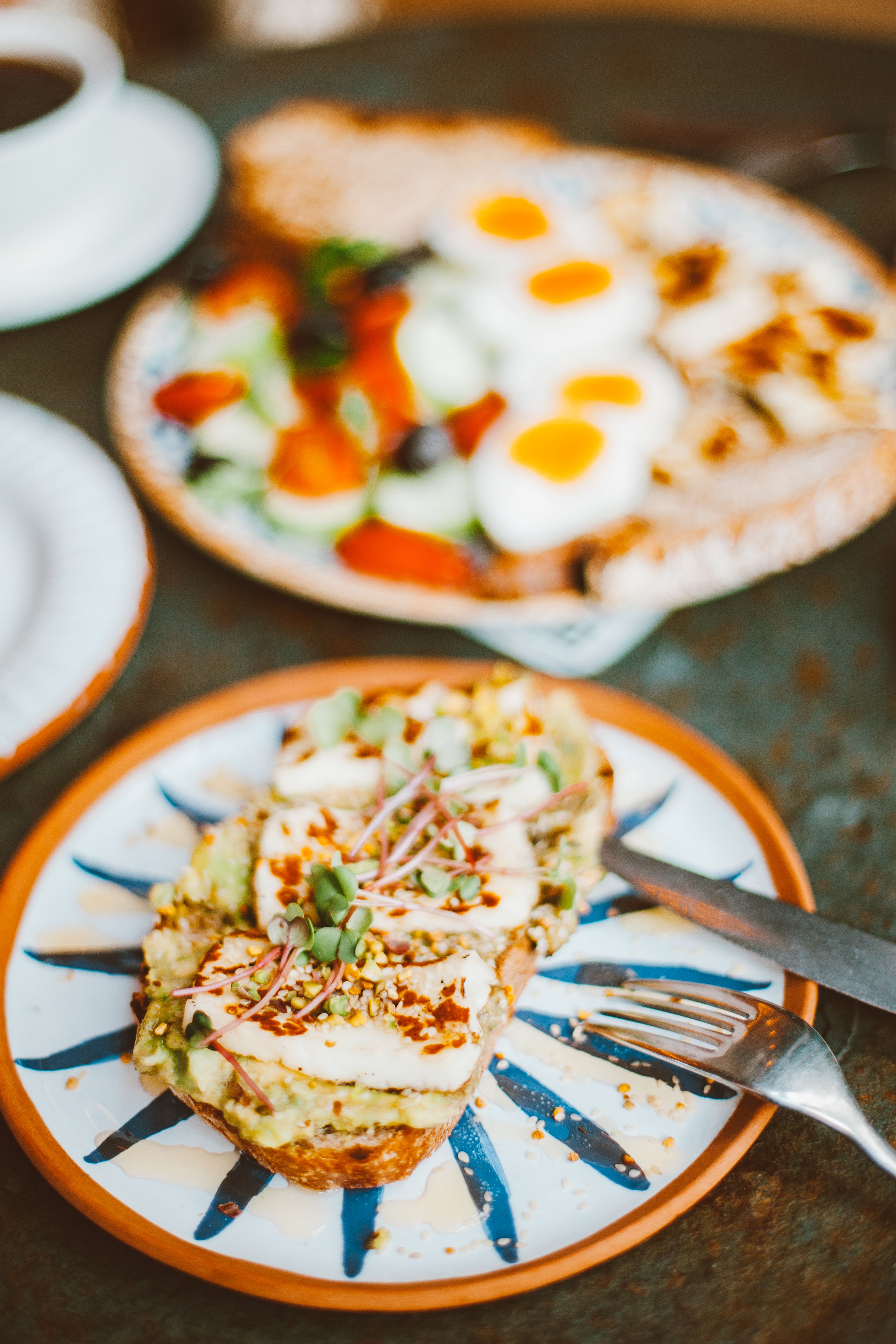 A delectable breakfast featuring avocado toast topped with microgreens and a vibrant salad with boiled eggs.