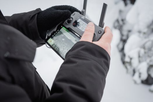 Close-up of hands operating a drone controller in snowy Finland. Winter technology adventure.