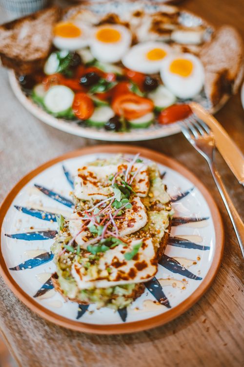 Free Plate of avocado toast with halloumi and a side of salad featuring boiled eggs. Stock Photo