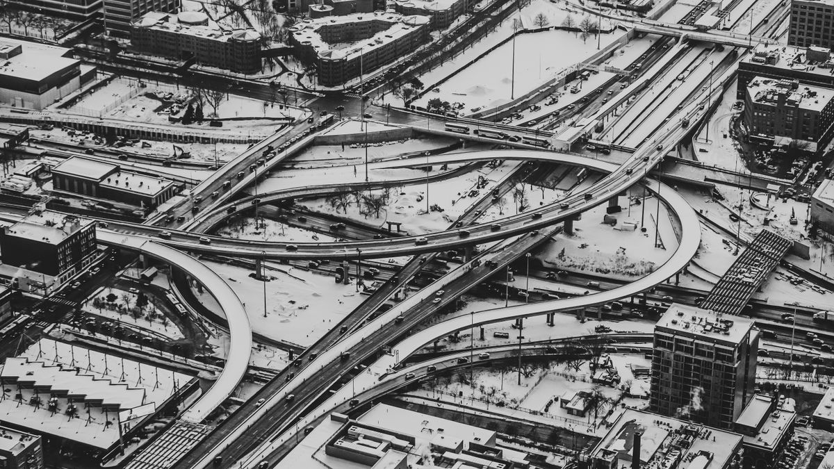 Stunning aerial view of a city highway interchange covered in snow, captured in black and white.