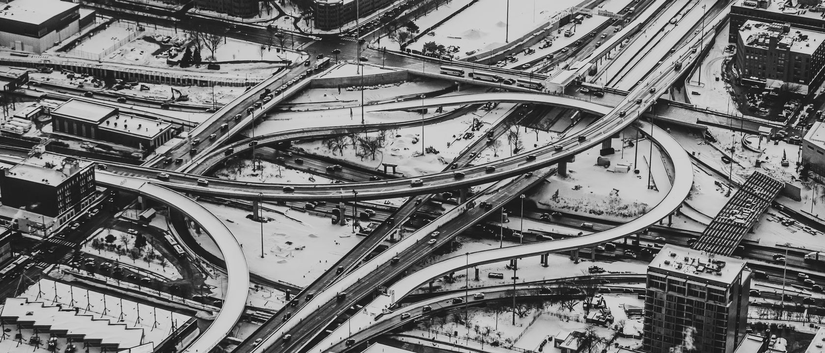 Stunning aerial view of a city highway interchange covered in snow, captured in black and white.