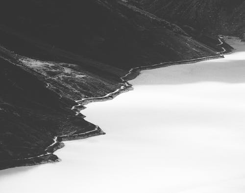 Grayscale Photo of Mountain Beside the Lake