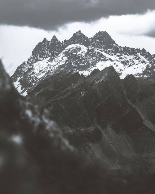 Free Captivating grayscale photo showcasing snow-covered mountain peaks under a cloudy sky. Stock Photo