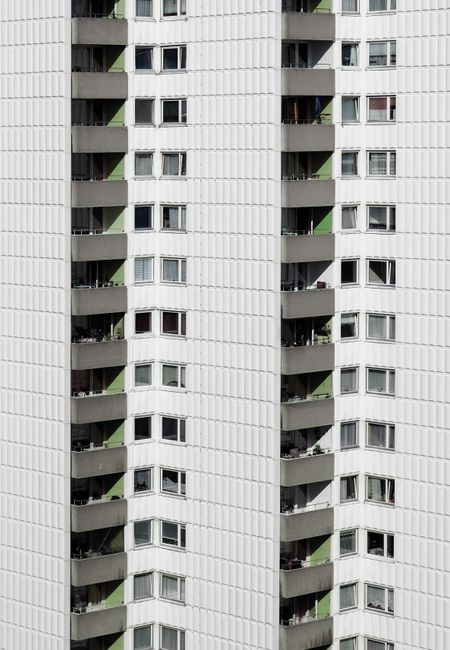Vertical view of a contemporary apartment building facade in Berlin, highlighting balconies and windows.