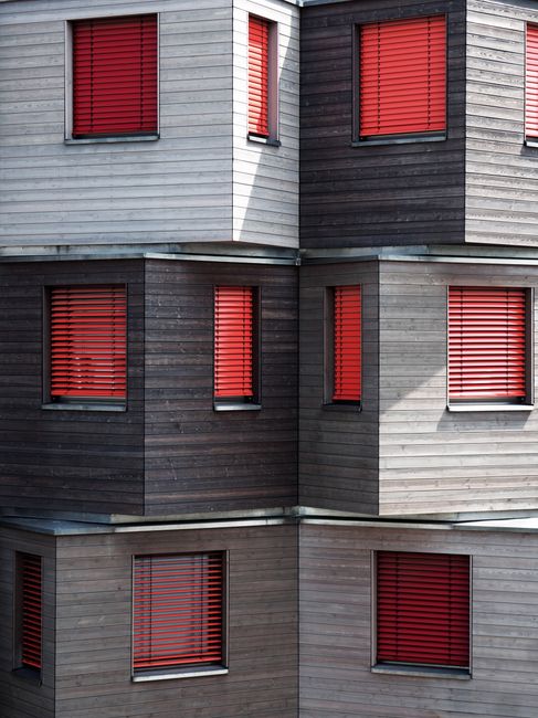 Close-up of a modern building facade with striking red window shutters in Berlin.