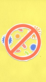 Overhead view of decorative cardboard appliques of prohibition symbol on different viruses and microbes on yellow background