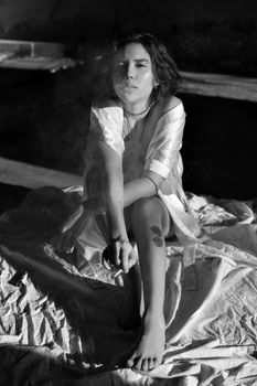Black and white portrait of a woman smoking in natural light, creating a dramatic effect.