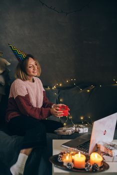 在视频通话中，一位戴着派对帽子的女人在室内交换礼物，充满了节日气氛