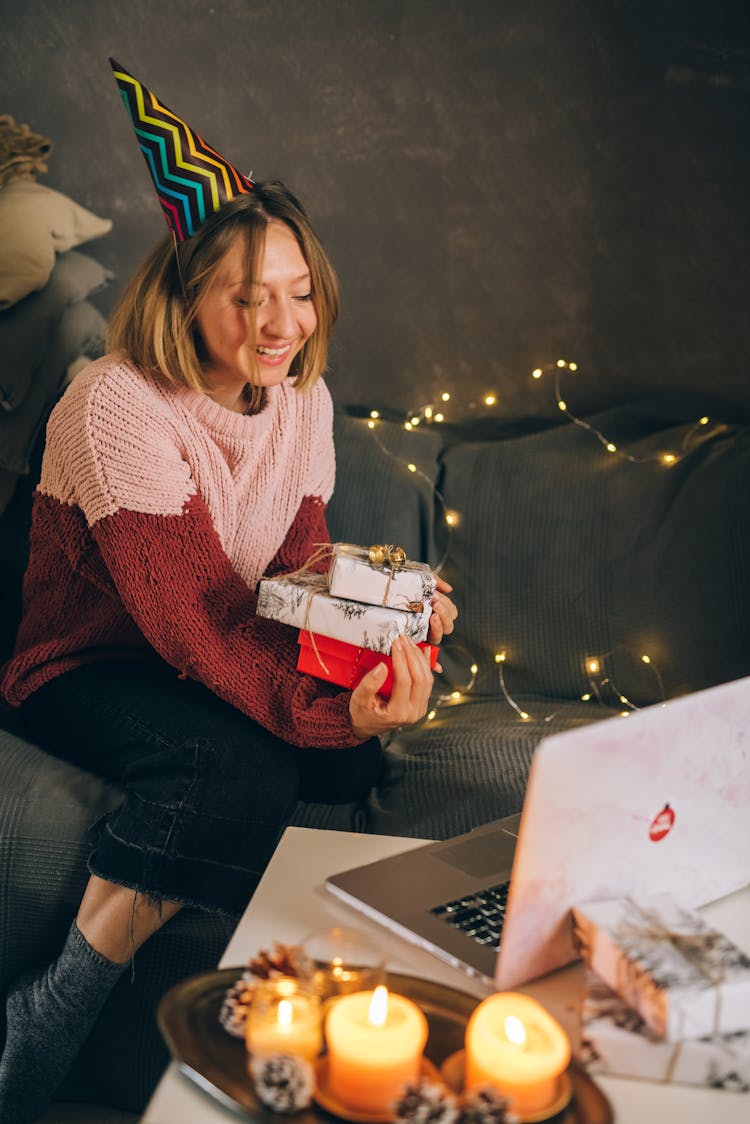 A Woman Holding Presents In Front Of A Laptop