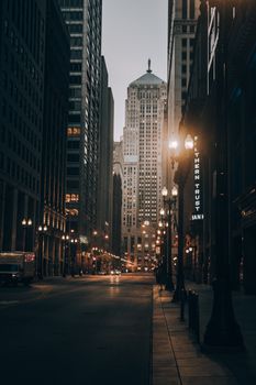 A serene nighttime street view in Chicago featuring illuminated skyscrapers and street lamps.