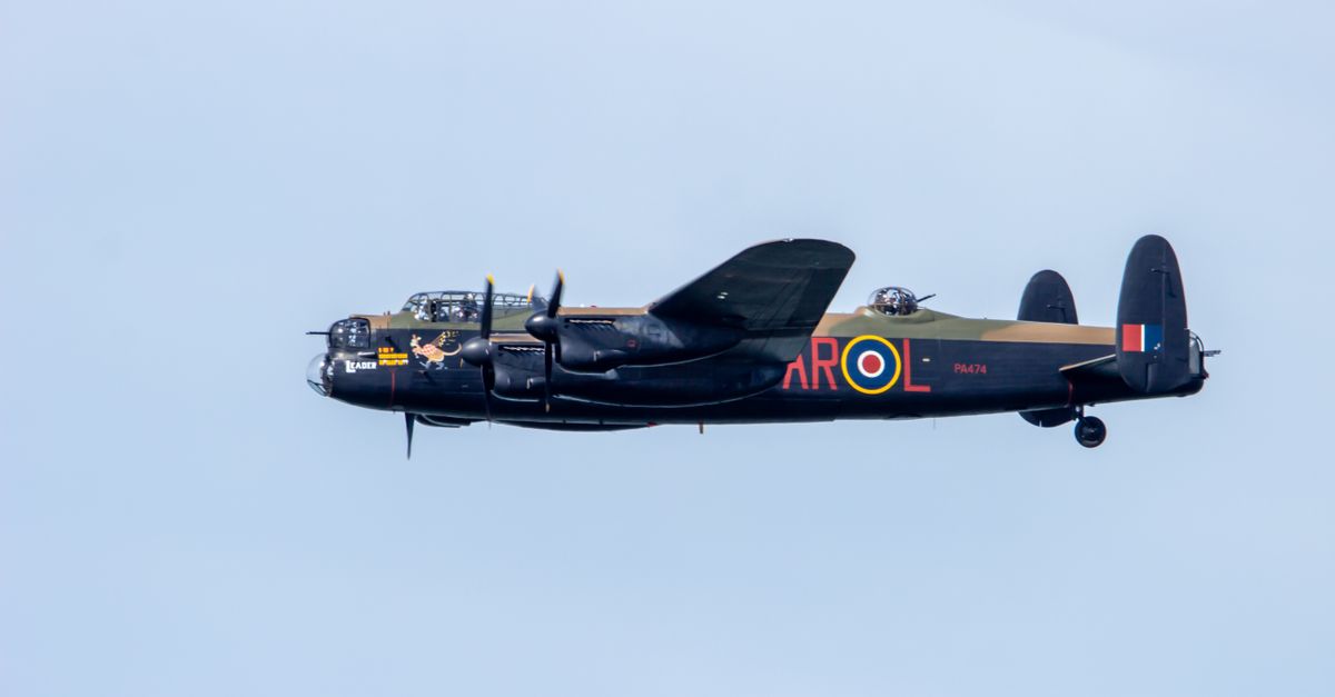 A vintage Lancaster bomber aircraft flying through a clear blue sky.