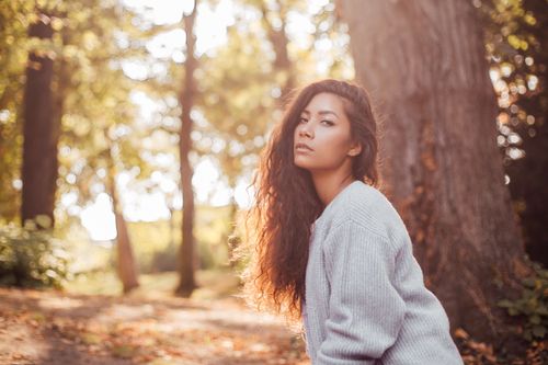 Free A serene portrait of a woman in a sunlit autumn forest, showcasing natural beauty. Stock Photo