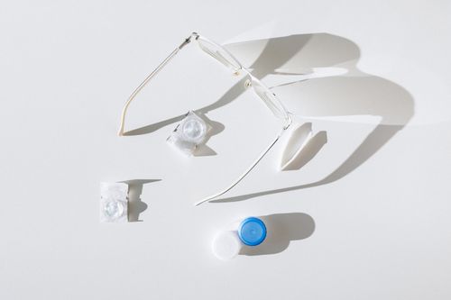 Free Flat lay of eyeglasses, contact lenses, and case on white background, emphasizing vision care. Stock Photo