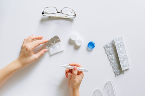 Free Flat lay setup of contact lenses with eyeglasses for eye care on a white background. Stock Photo