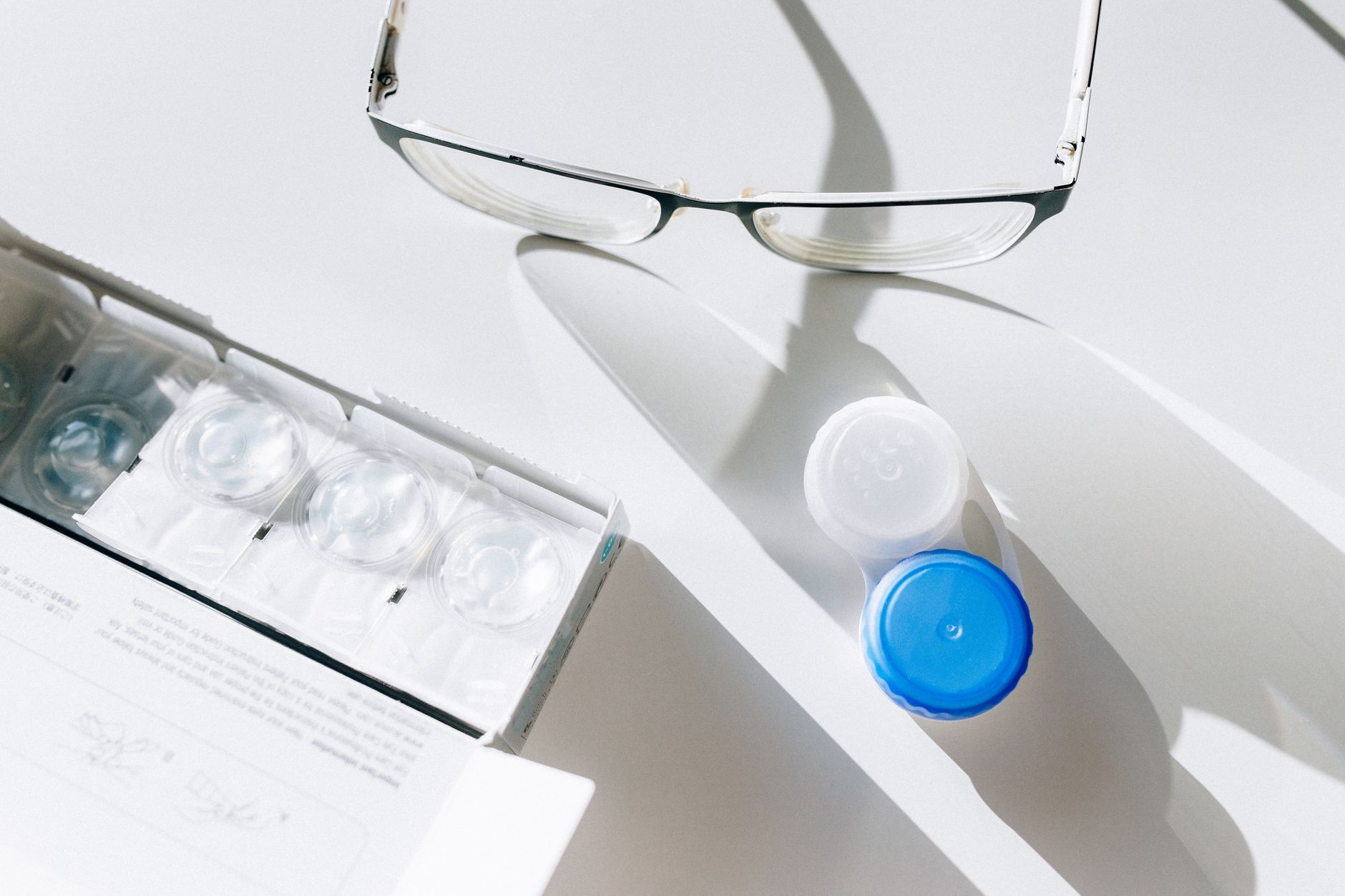 Flat lay of eyeglasses, contact lenses, and case highlighting everyday vision care essentials.