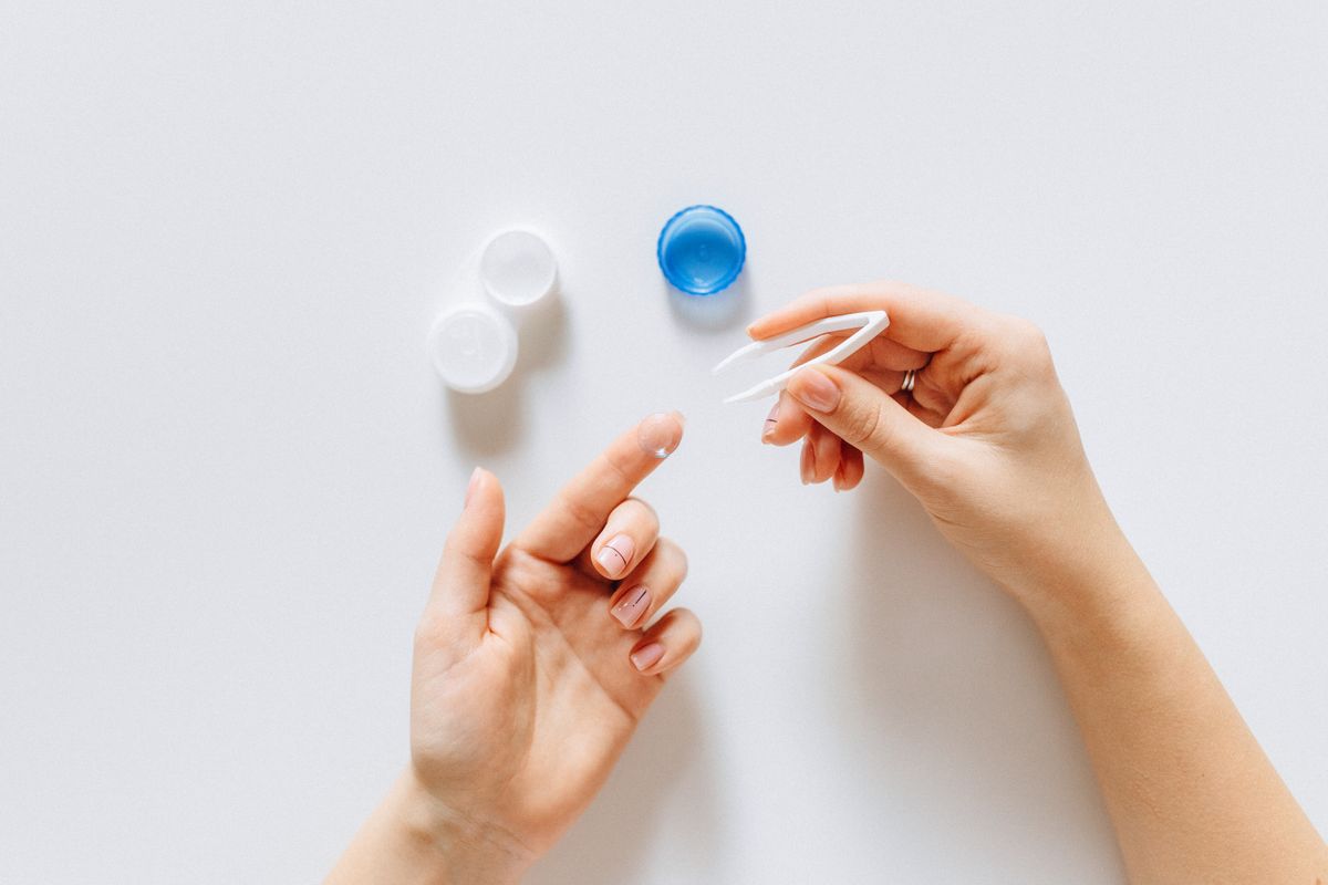 Tweezers, contact lens and lens case on a white background
