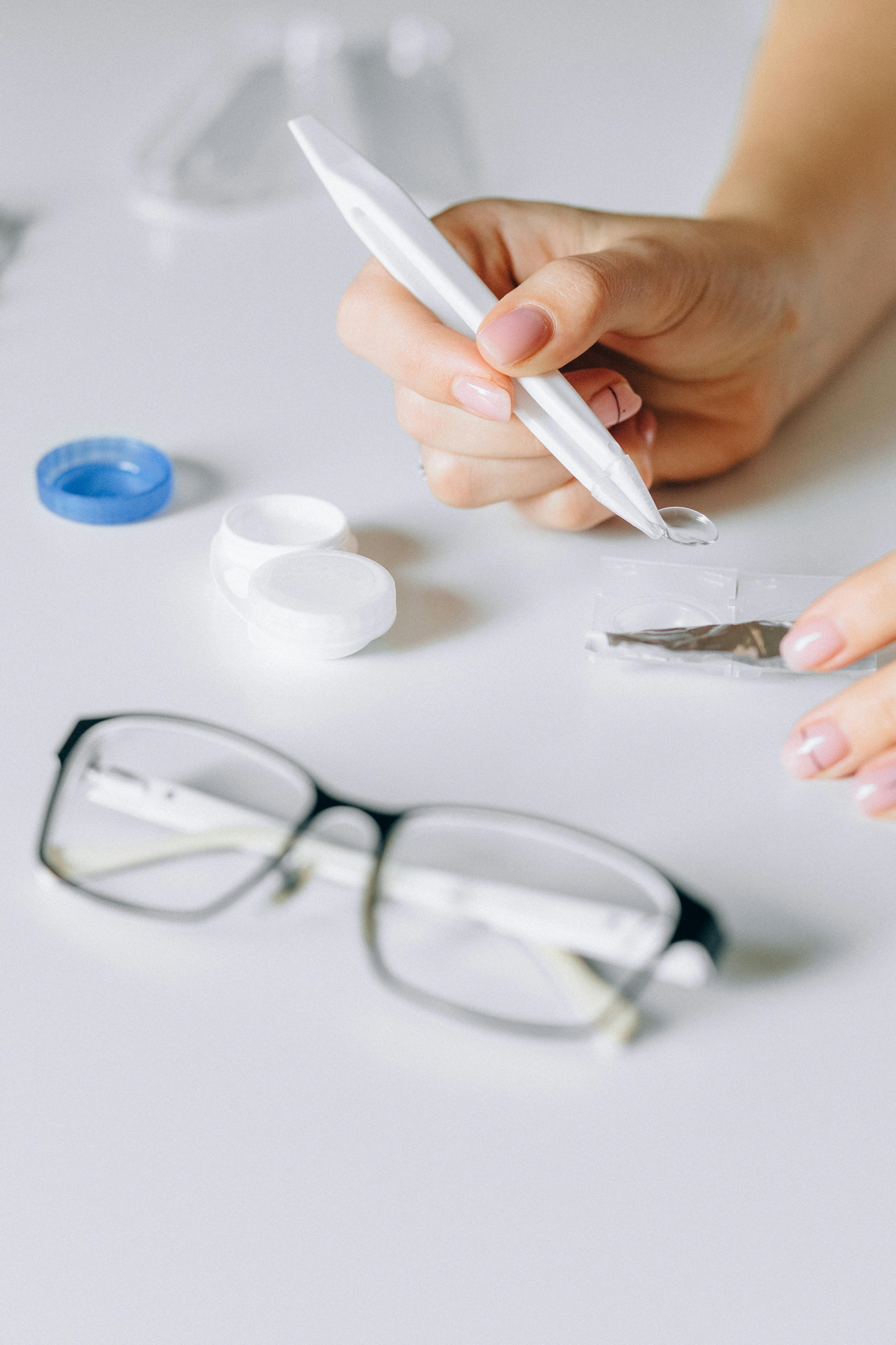 person holding white pen and eyeglasses
