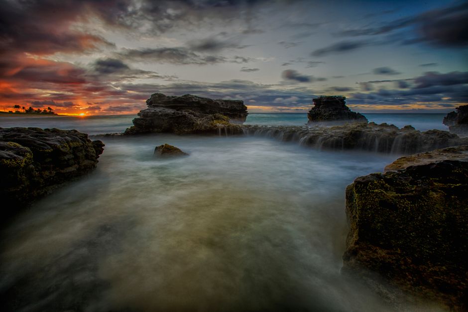 Boca Raton Faces Extreme UV Exposure and Coastal Rip Current Risk 2 Serene twilight seascape with rocky shore and vibrant sunset clouds. | BocaVibe