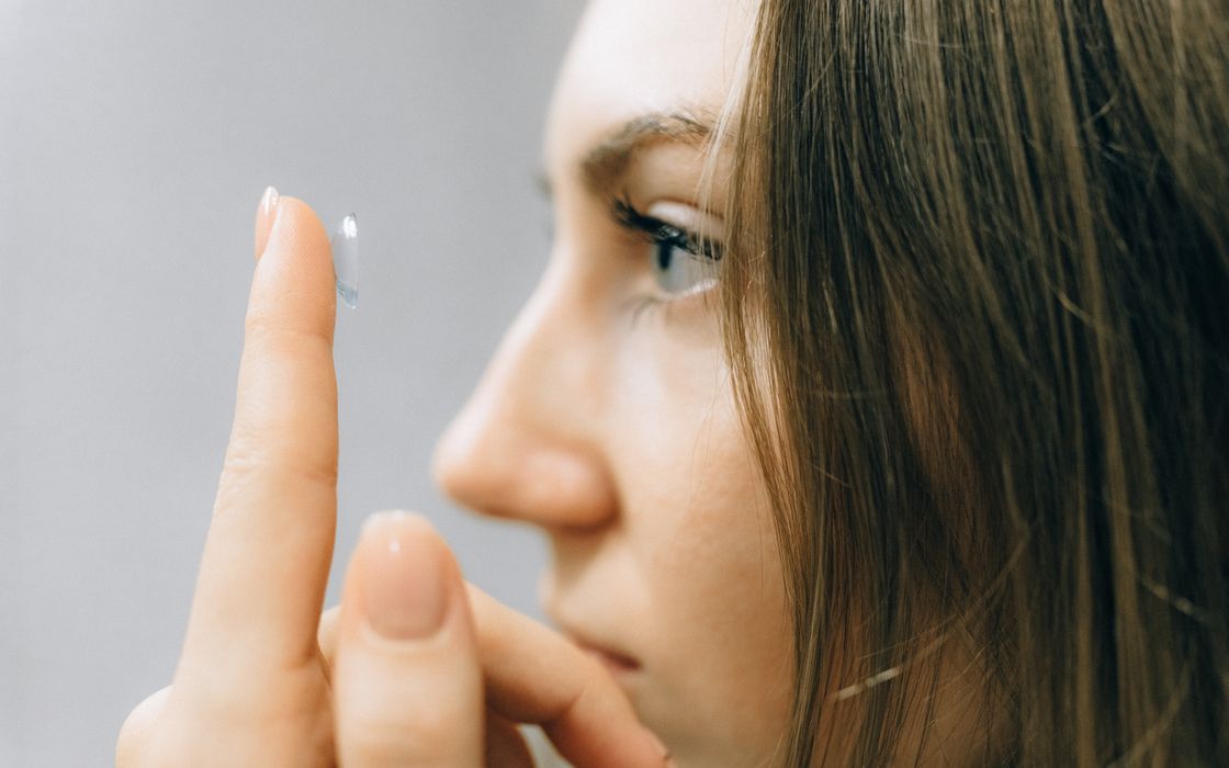 Young woman holding a contact lens on her fingertip just before putting it in