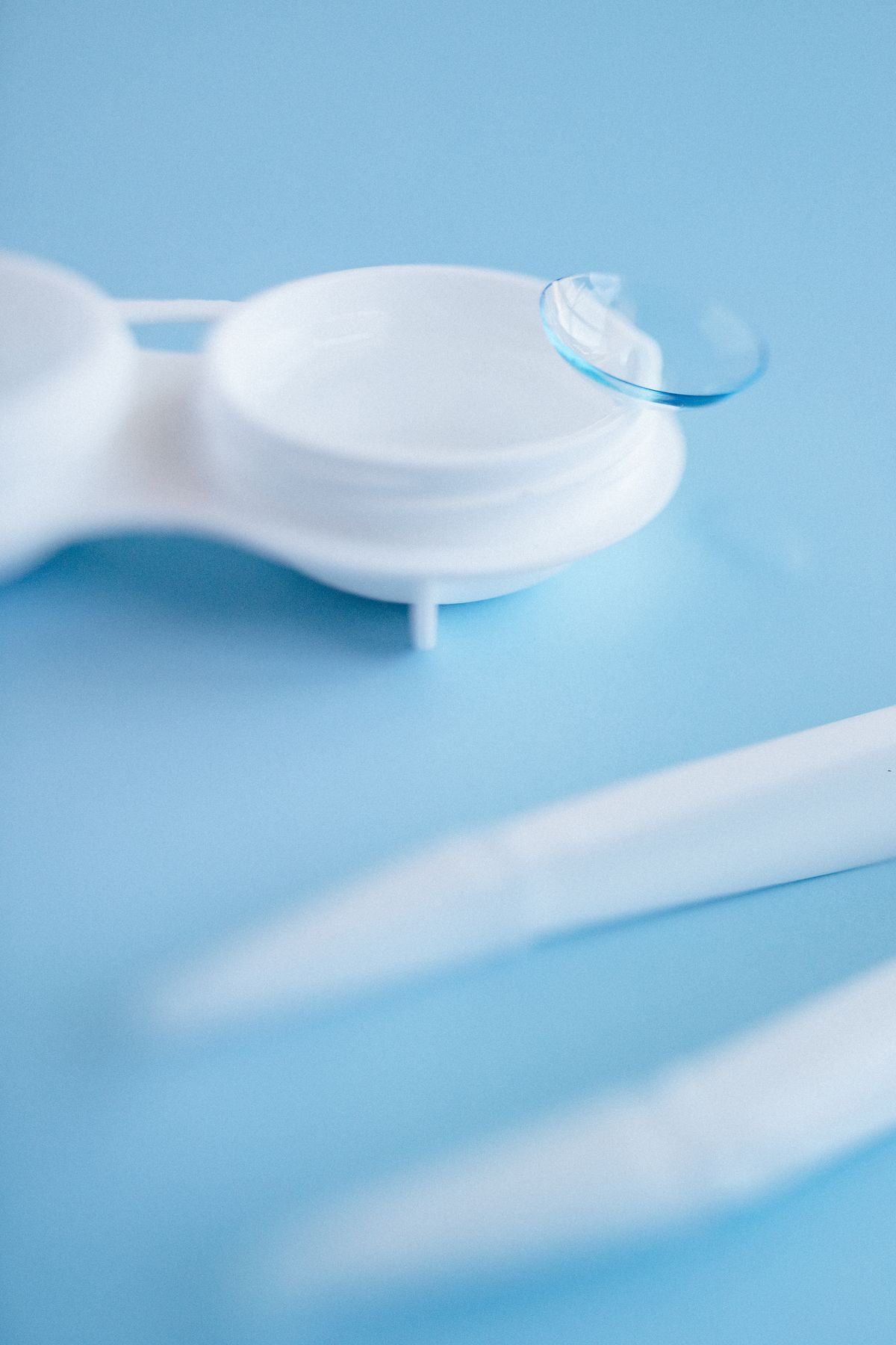 Contact lens and case on a blue studio background