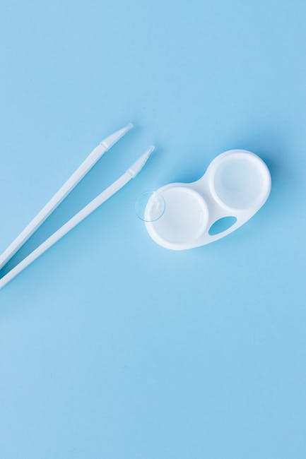 Top view of contact lens case and tweezers on a blue backdrop, ideal for eye care themes.