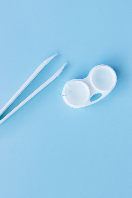 Free Top view of contact lens case and tweezers on a blue backdrop, ideal for eye care themes. Stock Photo