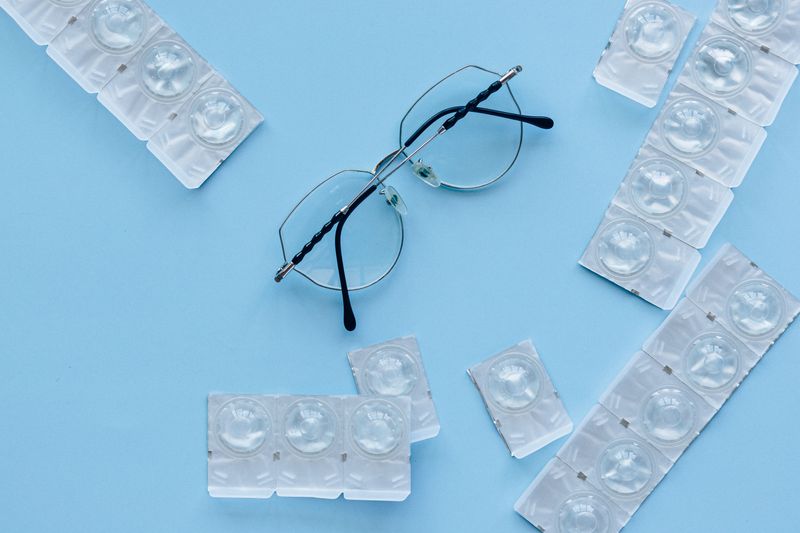 Lunettes et lentilles de contact posées sur une table, illustrant le coût des corrections optiques par rapport au SMILE