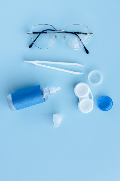 Silver Framed Eyeglasses Beside Blue Bottle