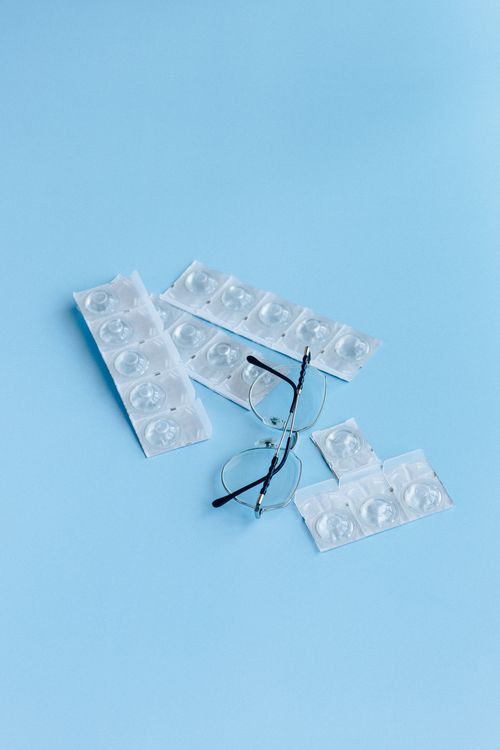 Free Eyeglasses and contact lenses laid out on a blue background. Ideal for eye care themes. Stock Photo