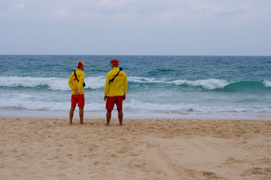 Two lifeguards in yellow and red uniforms surveying the beach at Surfers Paradise, Australia.