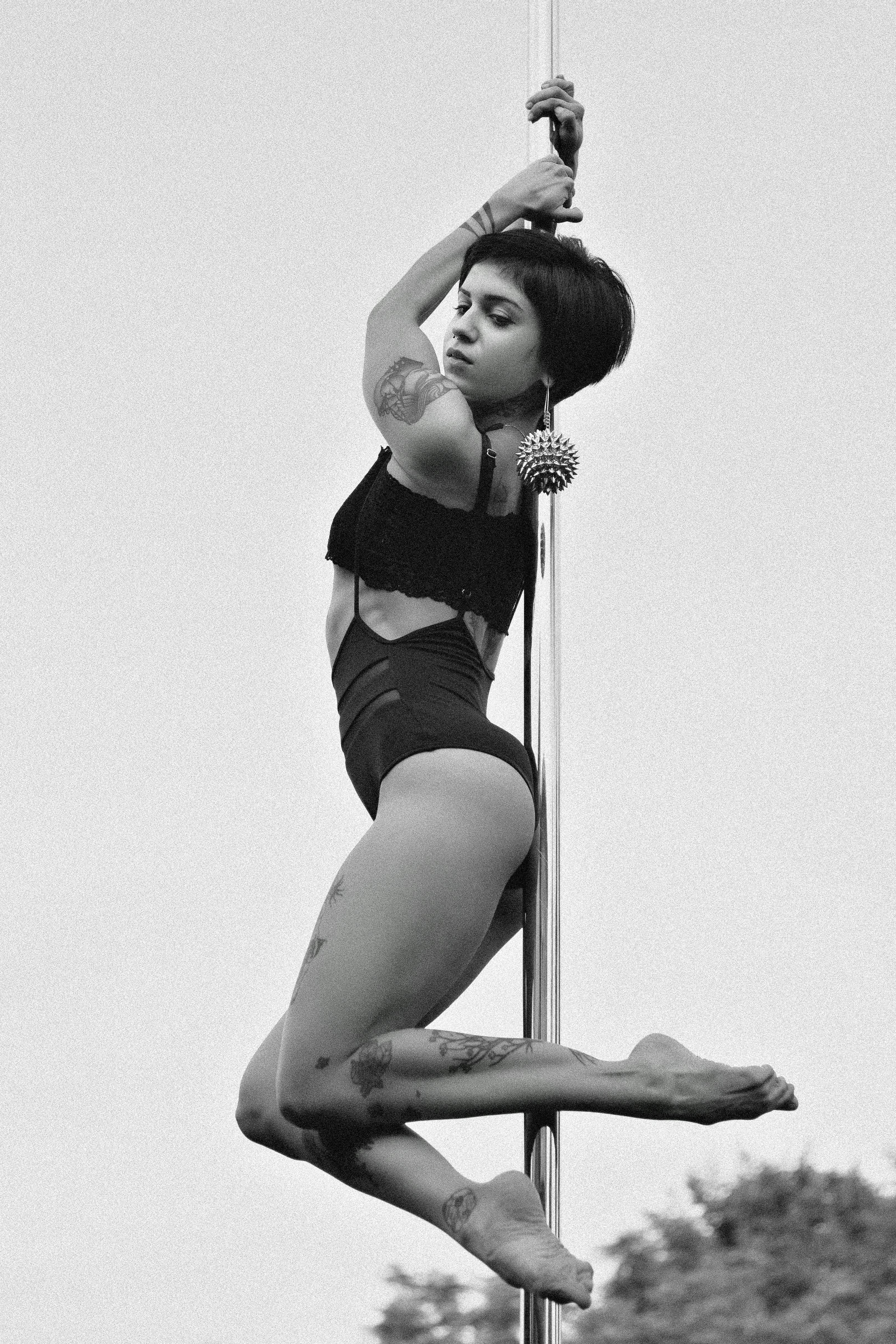 Graceful pole dancer captured in artistic black and white photography.