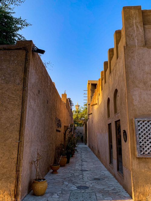 Free A narrow cobblestone alleyway in a traditional Middle Eastern architecture setting under a clear blue sky. Stock Photo