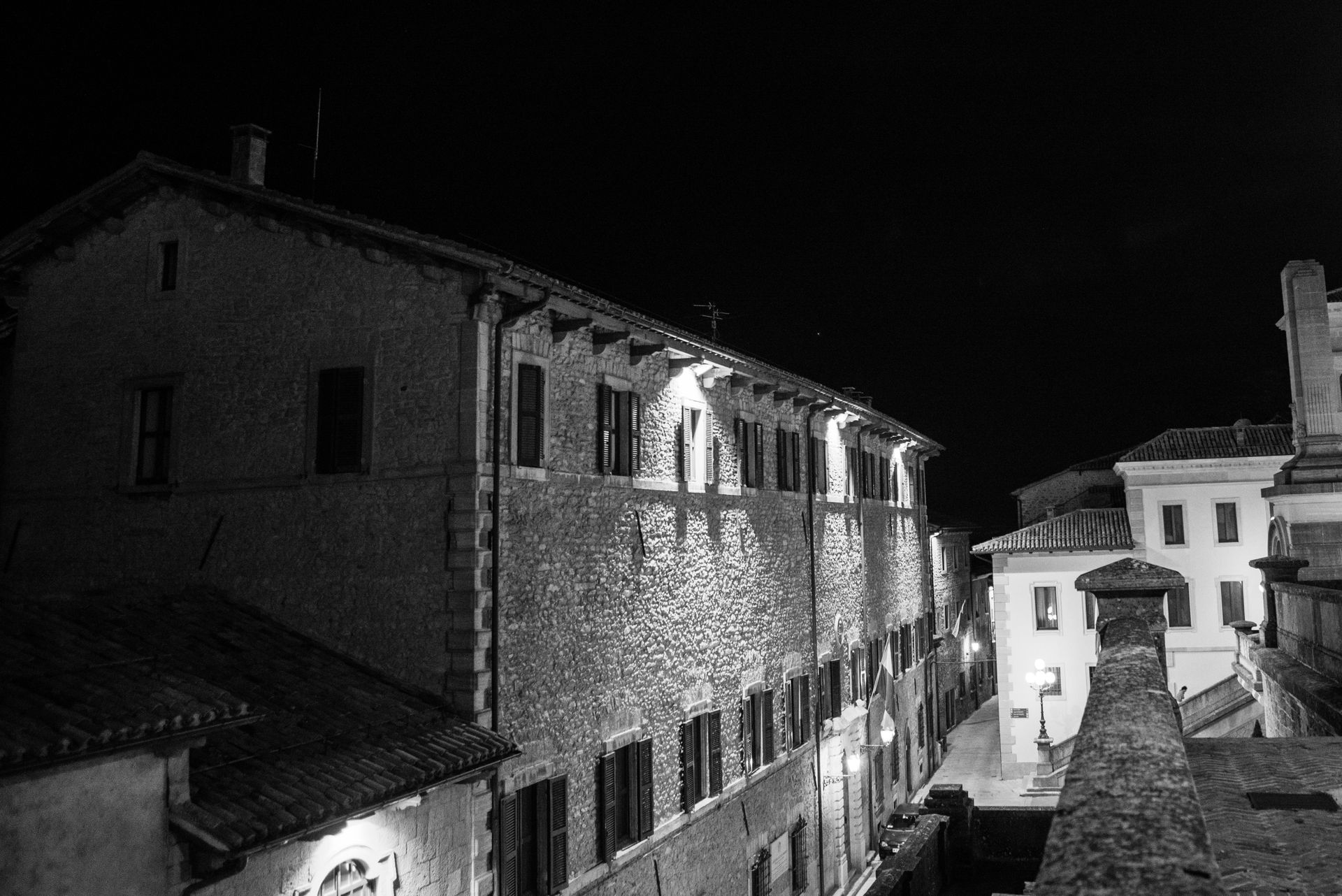 Black and white night view of a historic Italian village street with classic architecture.