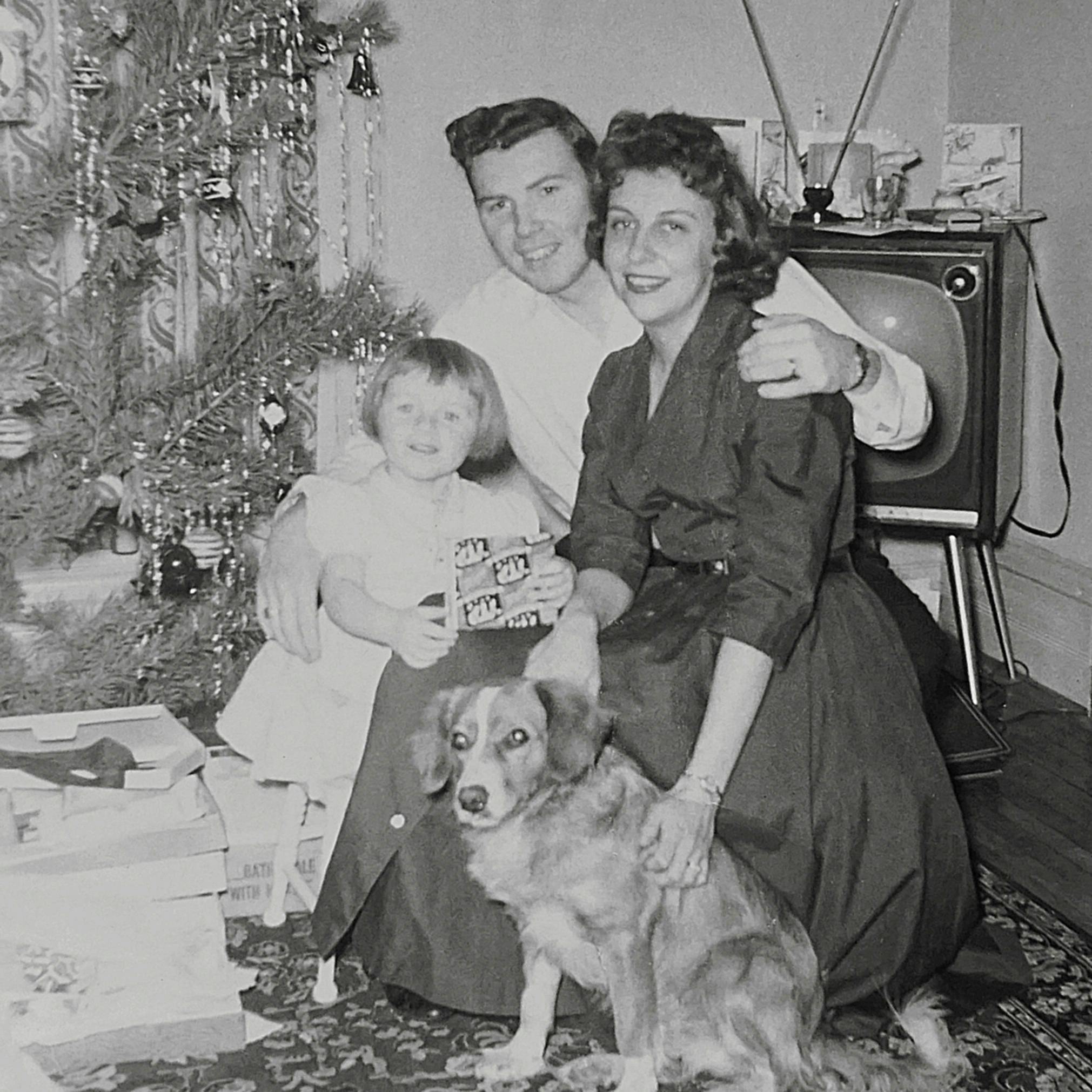 grayscale photo of family and pet posing near a christmas tree