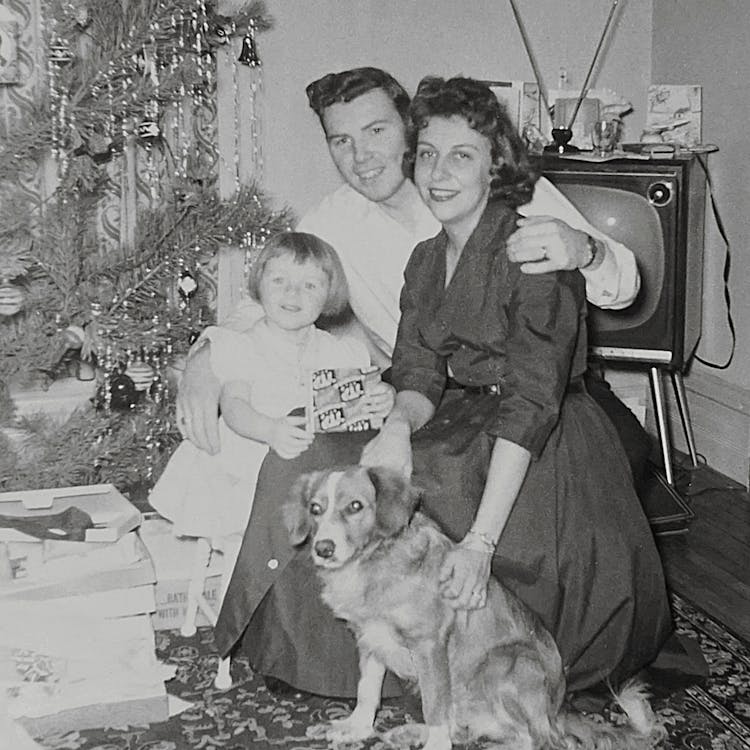 Grayscale Photo Of Family And Pet Posing Near A Christmas Tree 