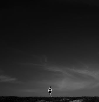Black and white low angle of female in summer outfit standing with hand on waist in grassy terrain