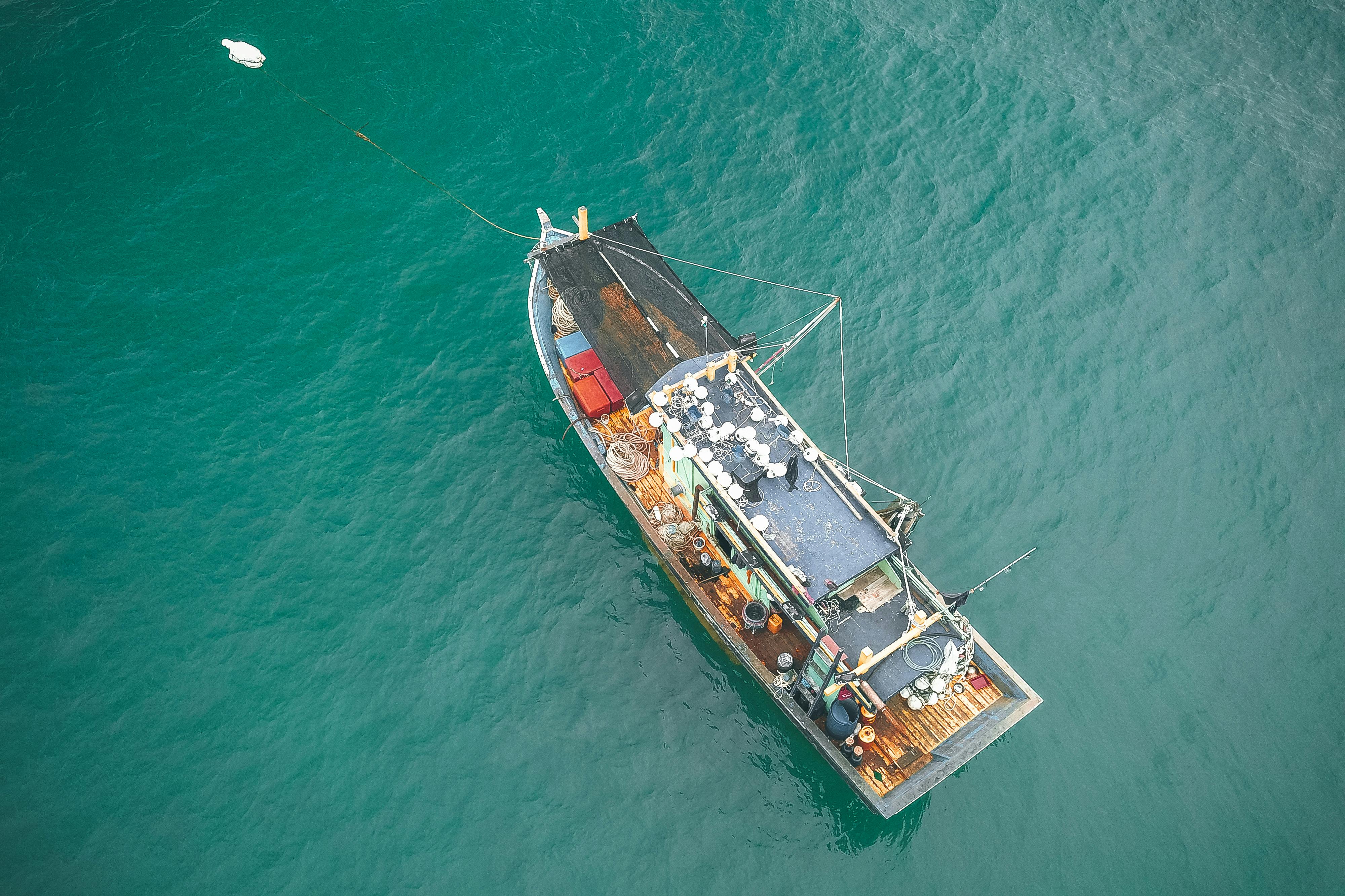 Aerial view of fishing boat floating on azure seawater · Free Stock Photo