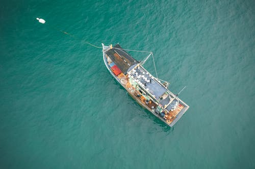 Free Drone view of big fishing vessel moored on rippling azure seawater on clear summer day Stock Photo