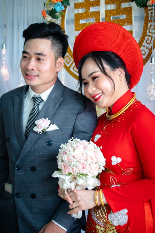 Free Happy Asian couple in traditional attire at their wedding, holding a bouquet. Stock Photo