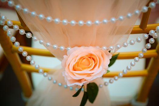 婚礼或活动中装饰有桃花、玫瑰和珍珠串的椅子特写