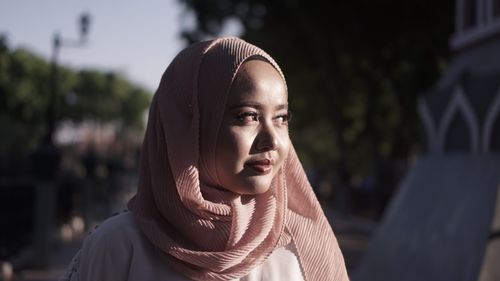 Free A serene portrait of a woman in a pink hijab, softly illuminated by natural light outdoors. Stock Photo
