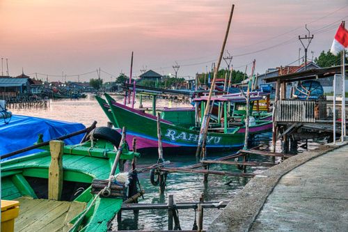Free Assorted boats moored on rippled lake between house facades in urban harbor under cloudy sky in evening Stock Photo