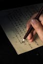 Close-Up Shot of a Person Writing on a Paper Using a Quill