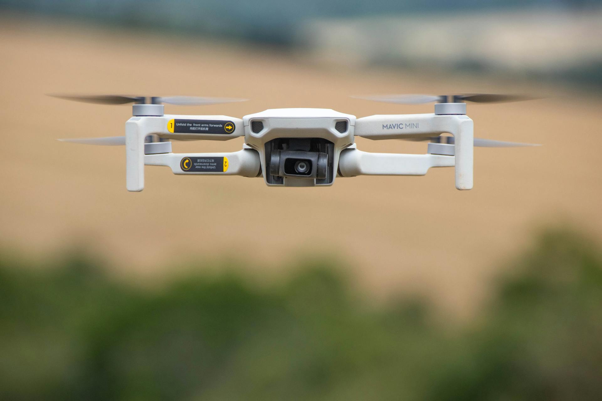 Close-up of a drone camera flying outdoors with a blurred background.