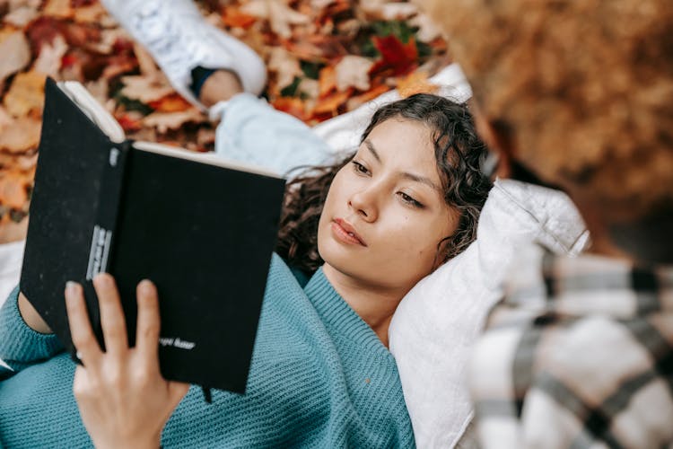 Thoughtful Hispanic Woman With Book Resting In Park