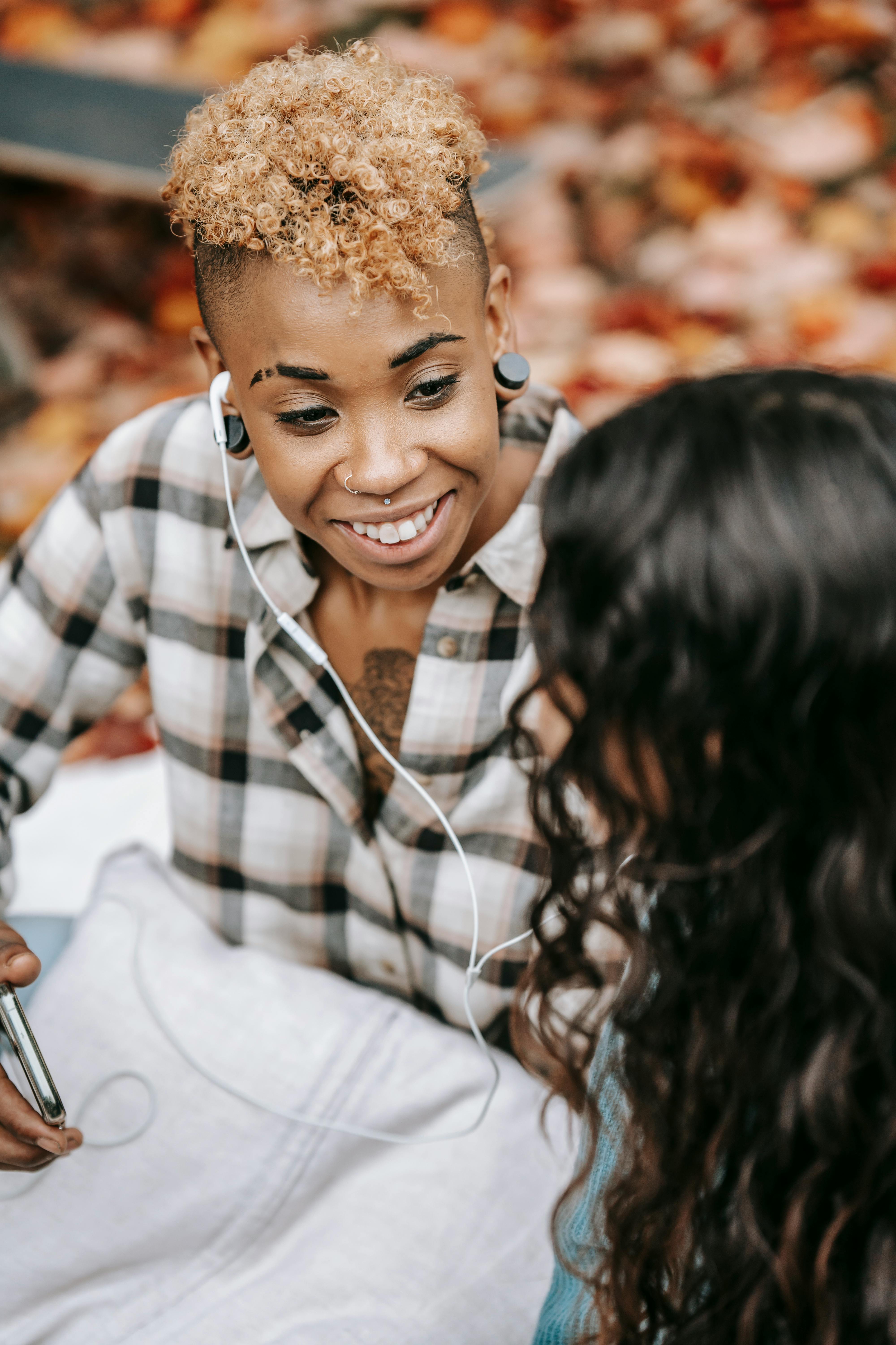 smiling black female listening to music with friend in earphones