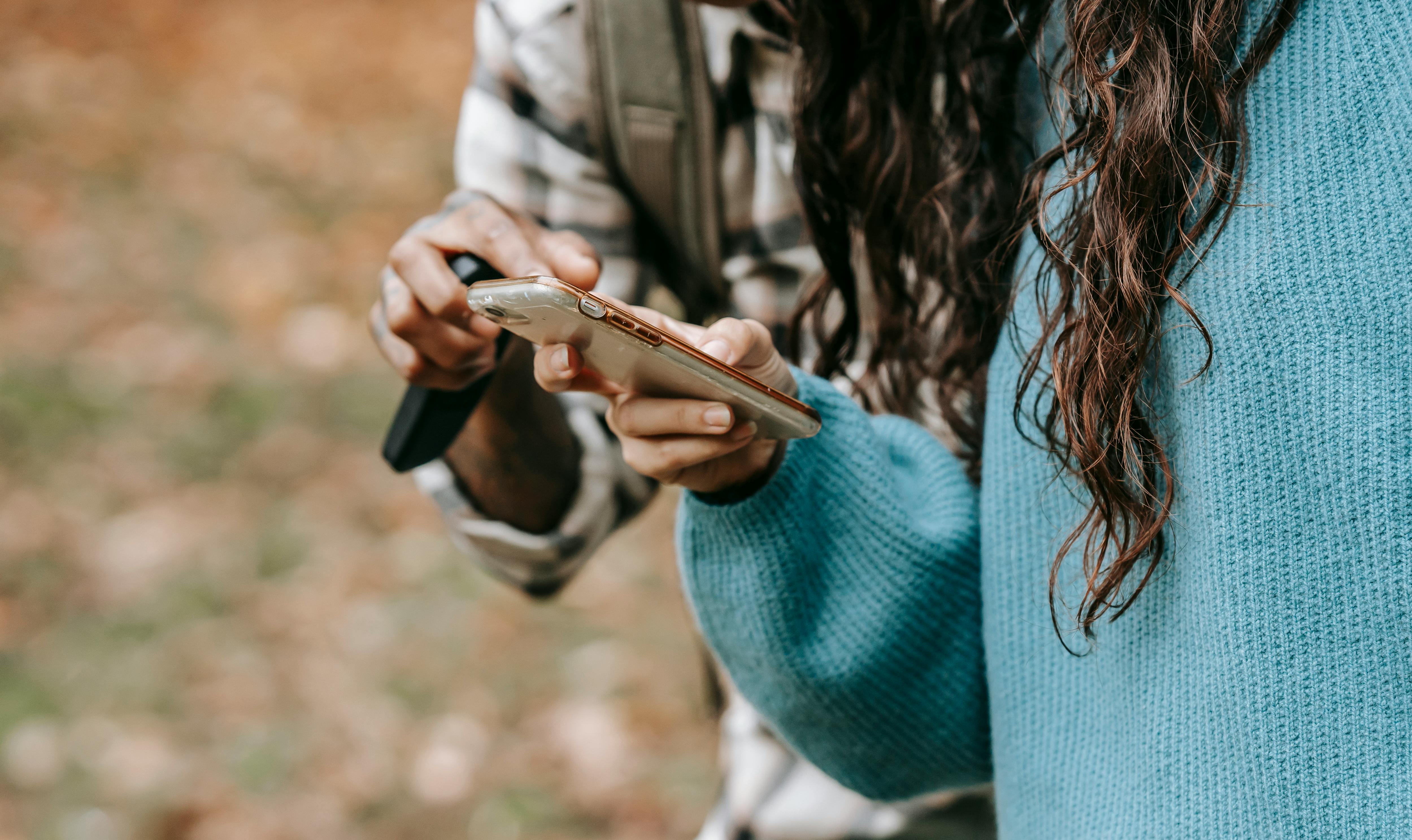 crop couple browsing smartphone in park