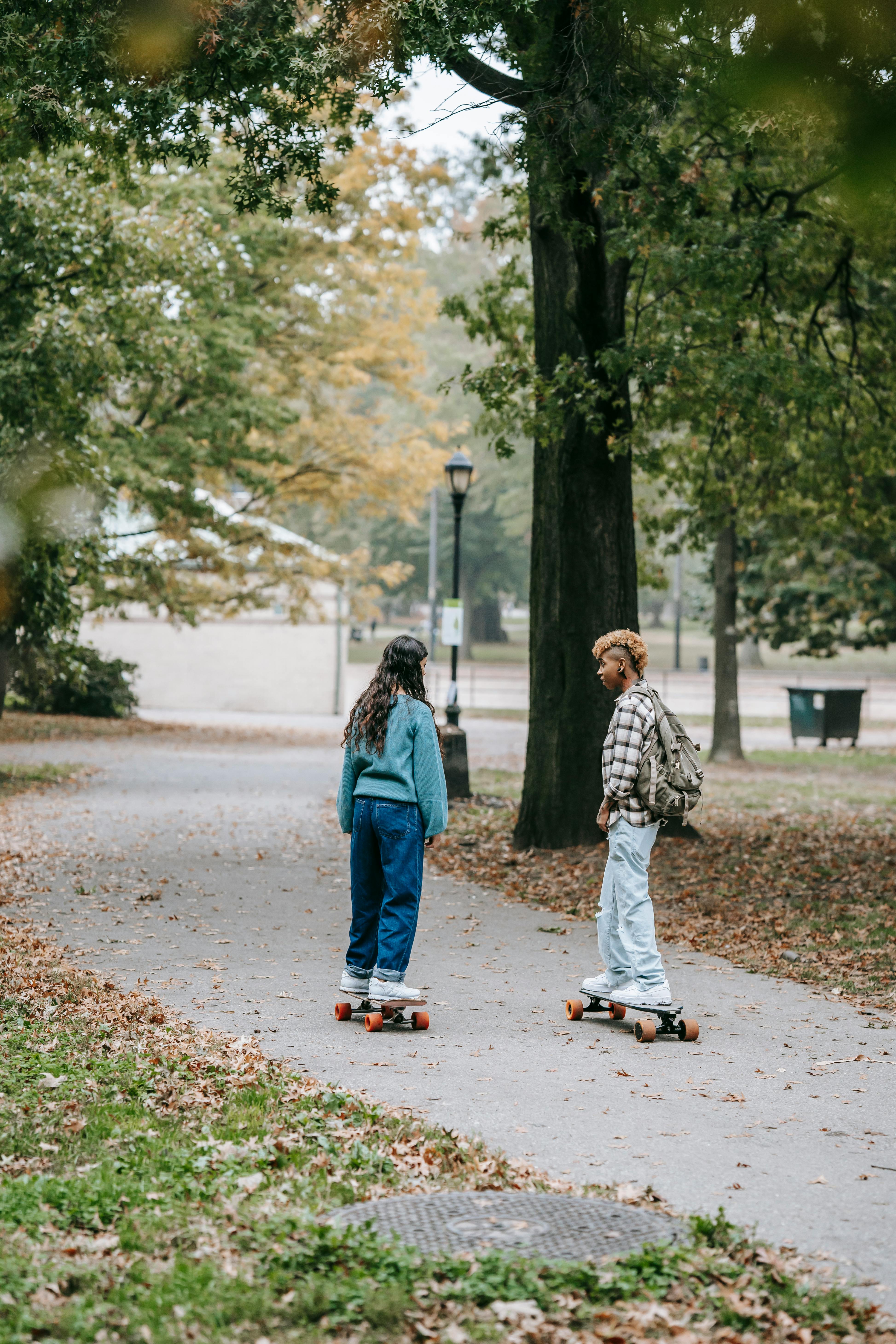 lesbian couple riding skateboards in park