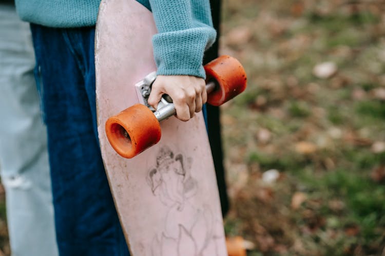 Crop Woman Holding Longboard In Park