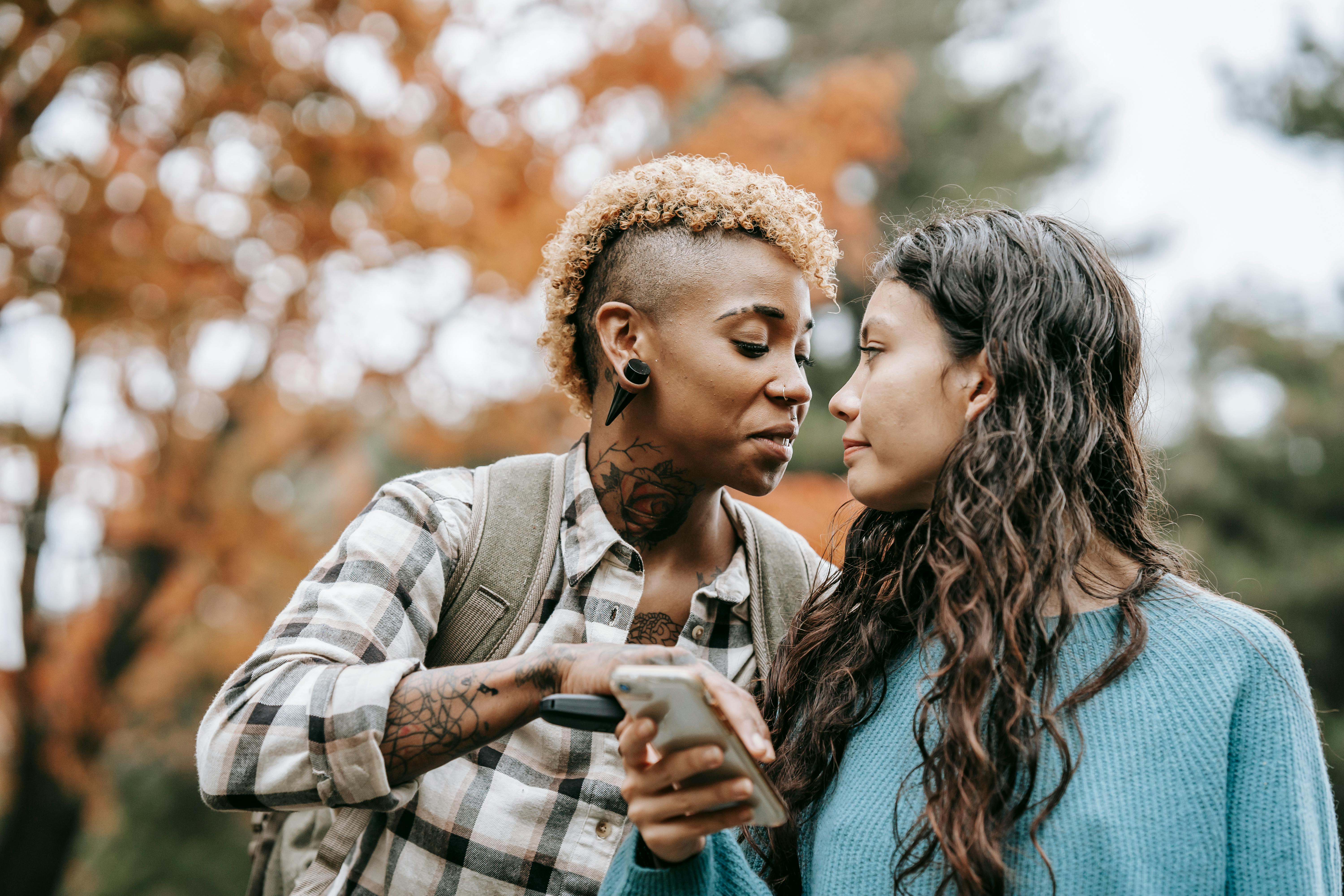 romantic multiracial homosexual couple using smartphone